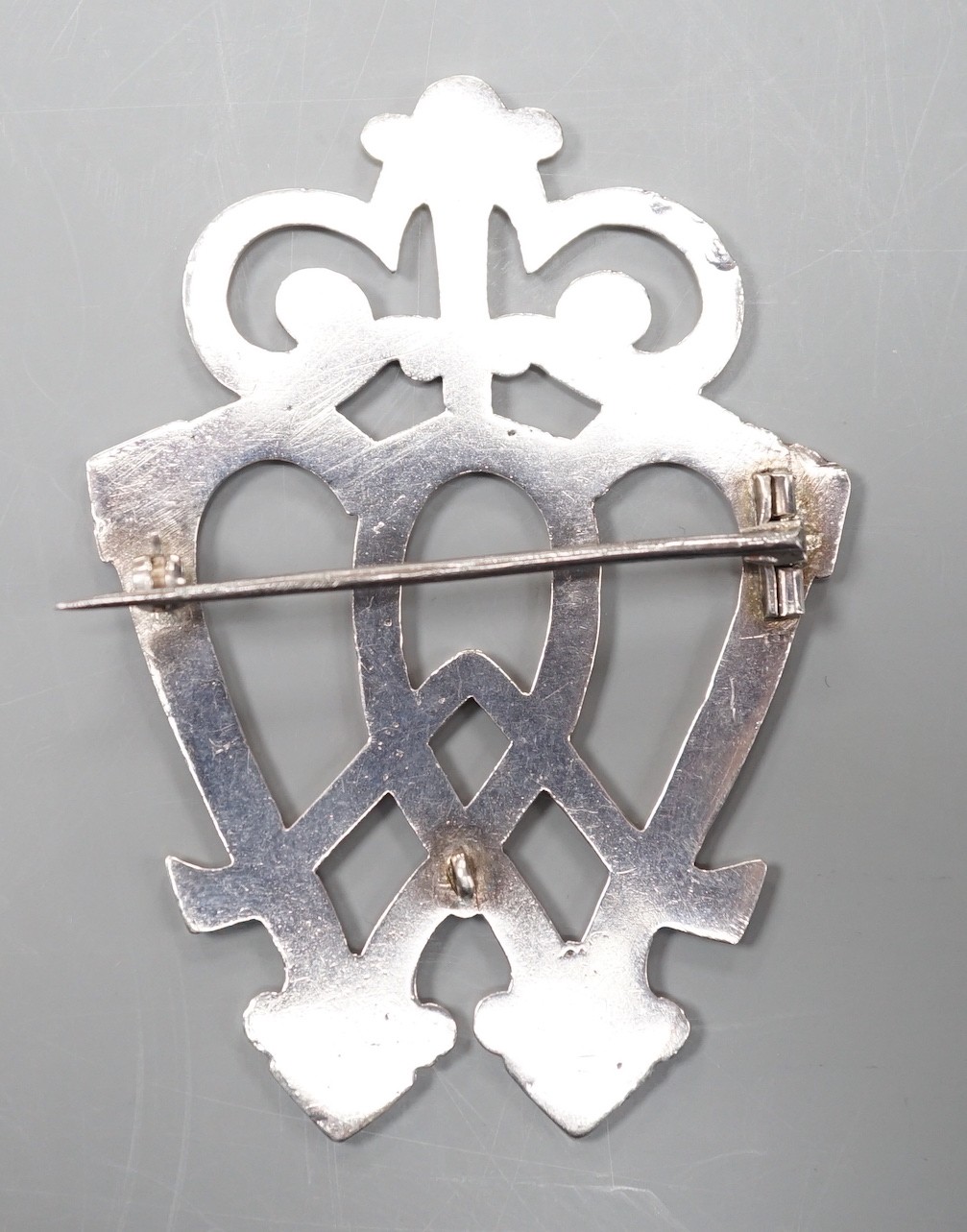 A white metal entwined twin heart brooch, with scrolling terminal, unmarked, 70mm.